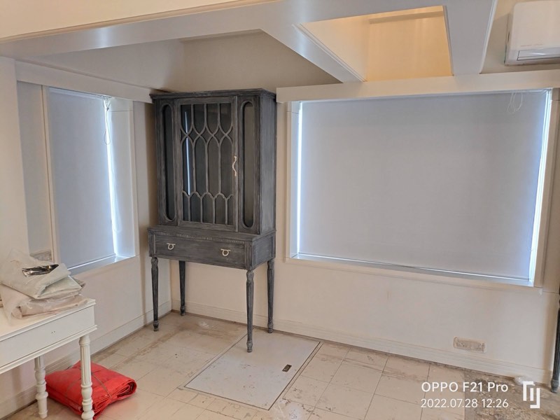 White blackout roller blinds either side of a cabinet