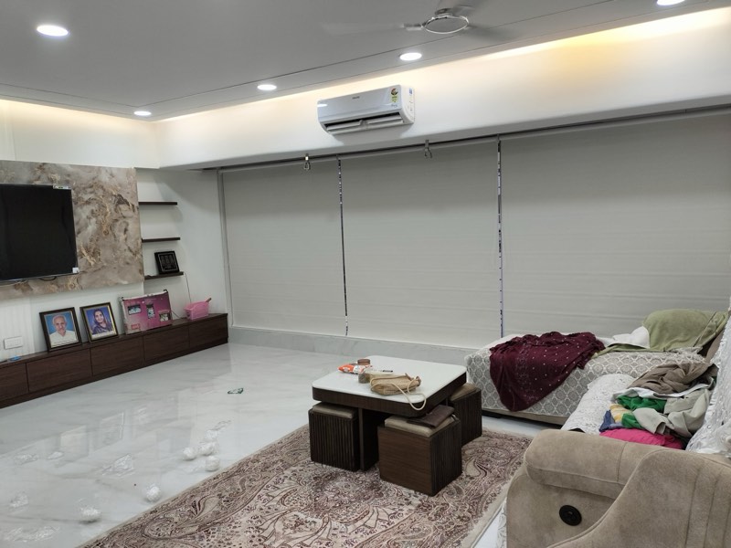 Three white roller blinds across a living-room wall