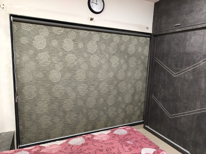 Grey damask-patterned roller blind behind a bed