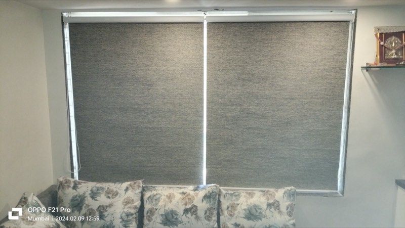 Pair of grey roller blinds behind a floral sofa